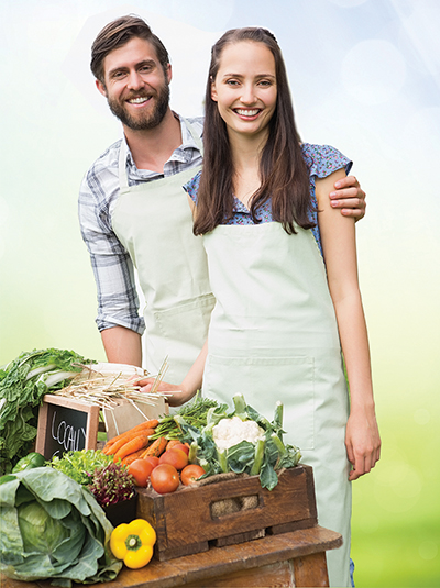 Couple selling organic vegetables at market on a sunny day